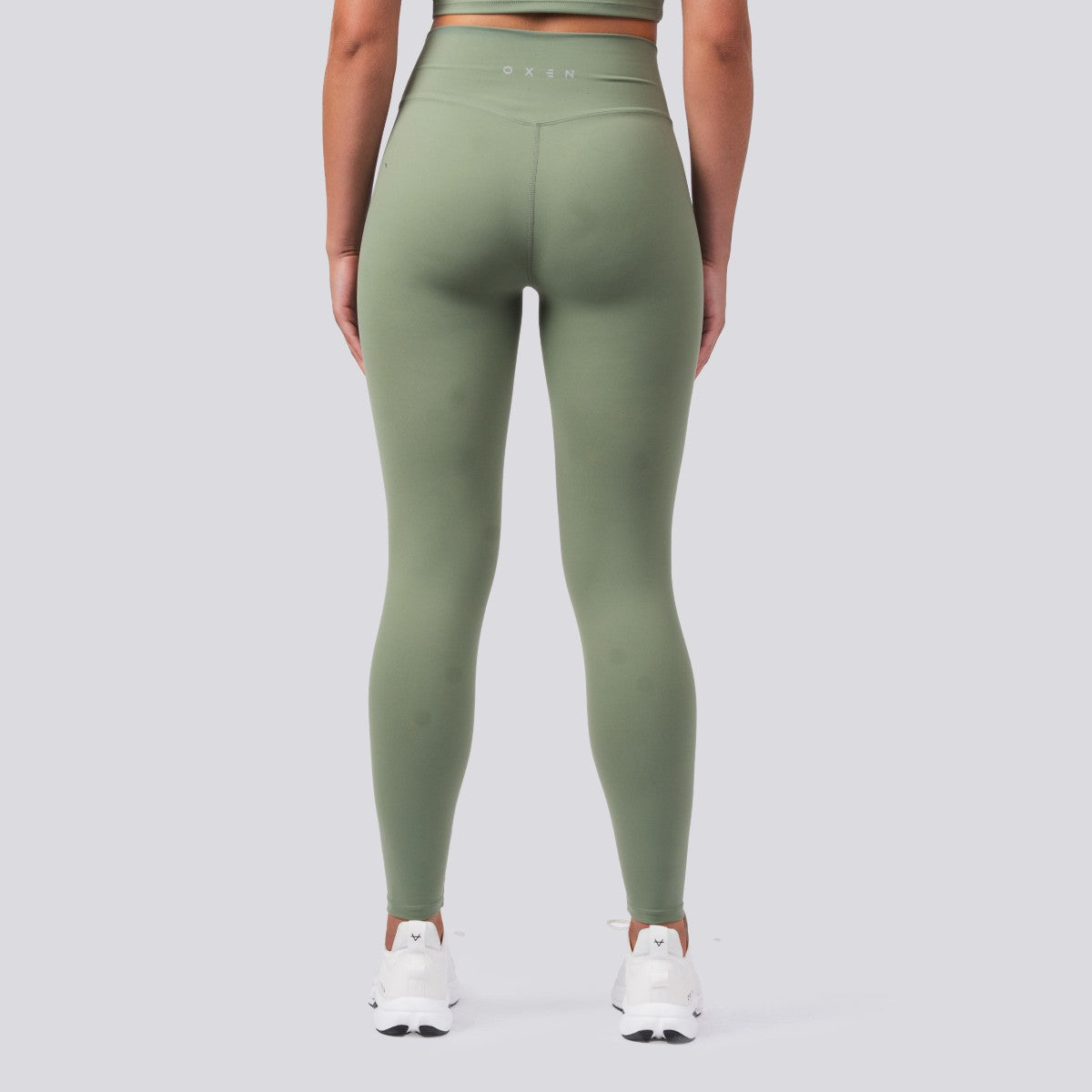 Person wearing green leggings on a plain background