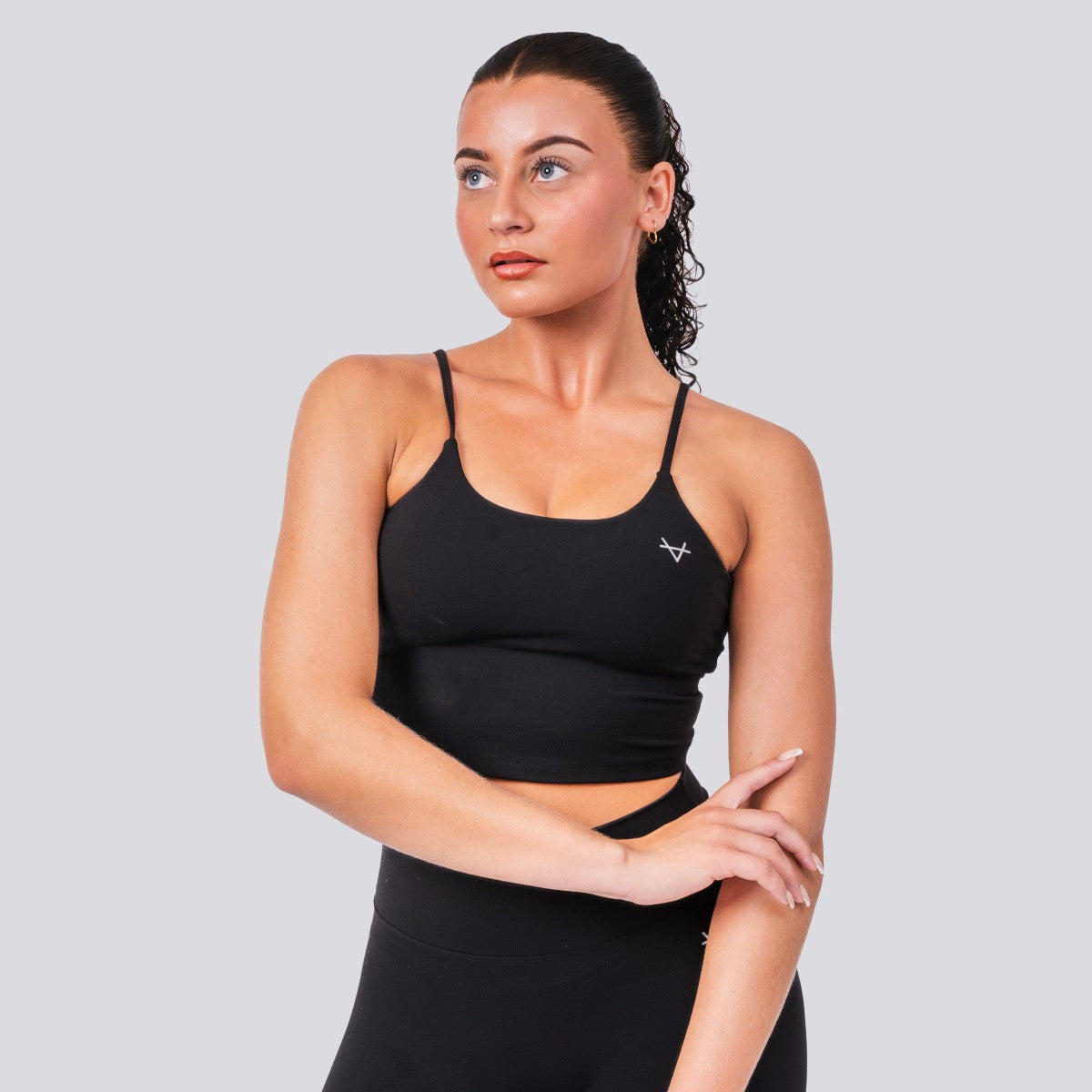 Woman wearing a black sports bra with a logo on a light gray background