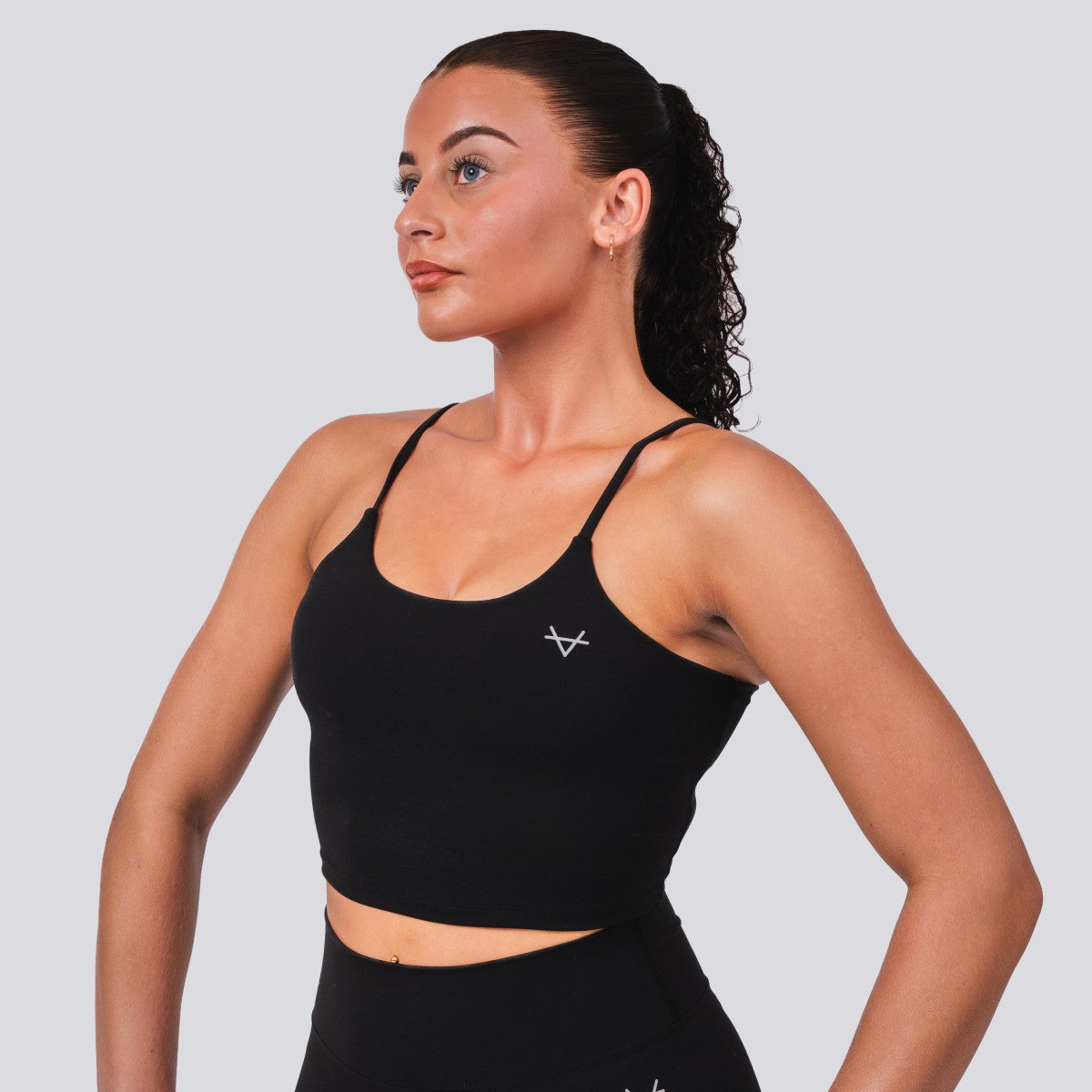 Woman wearing a black sports bra with a logo on a light gray background