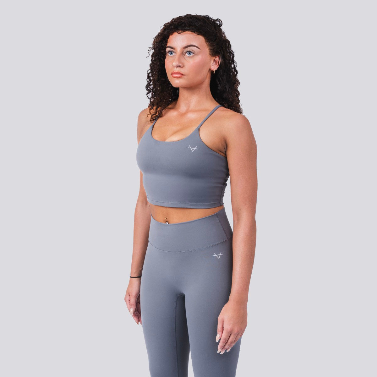 Woman wearing a gray athletic outfit with a plain background