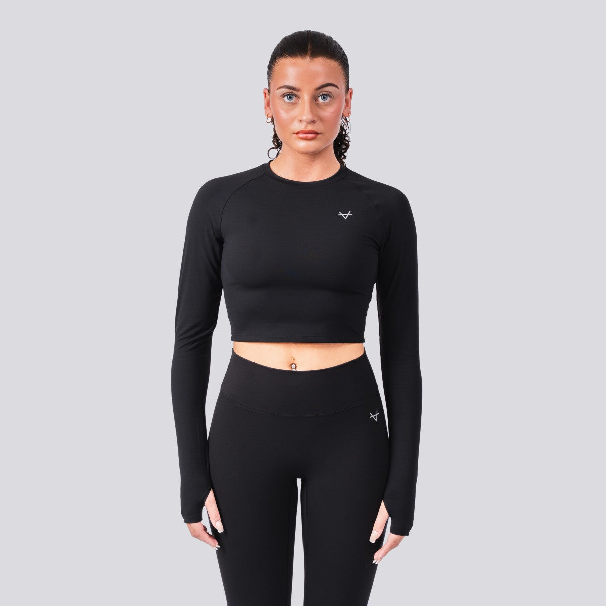 Woman wearing a black long-sleeve athletic top and leggings on a gray background