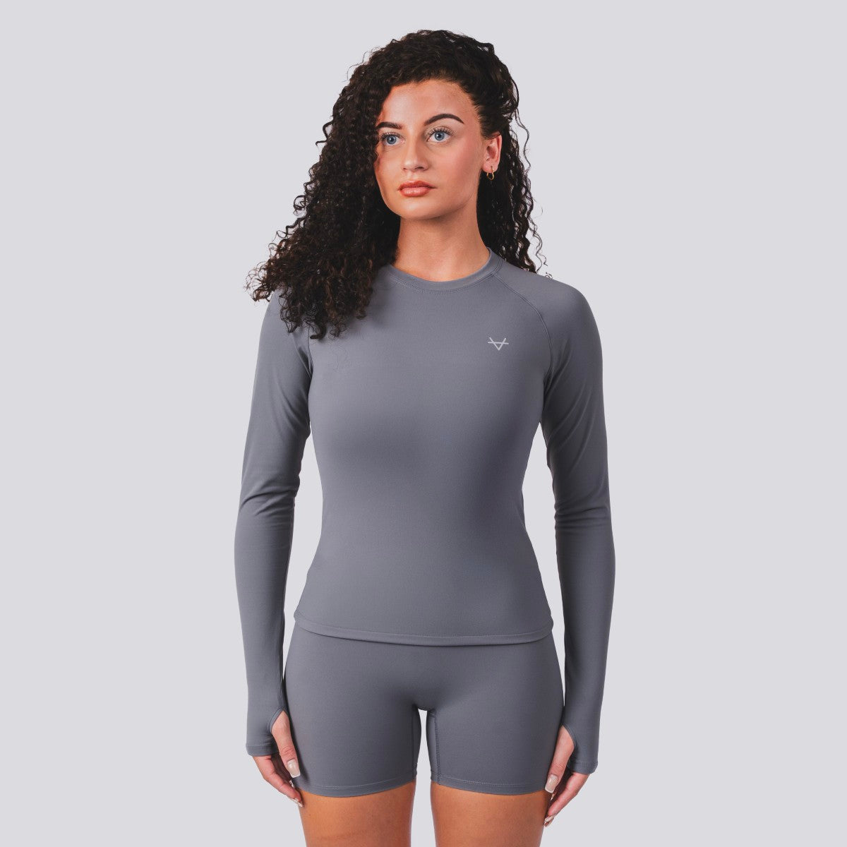 Woman wearing a gray long-sleeve top and shorts set on a light gray background