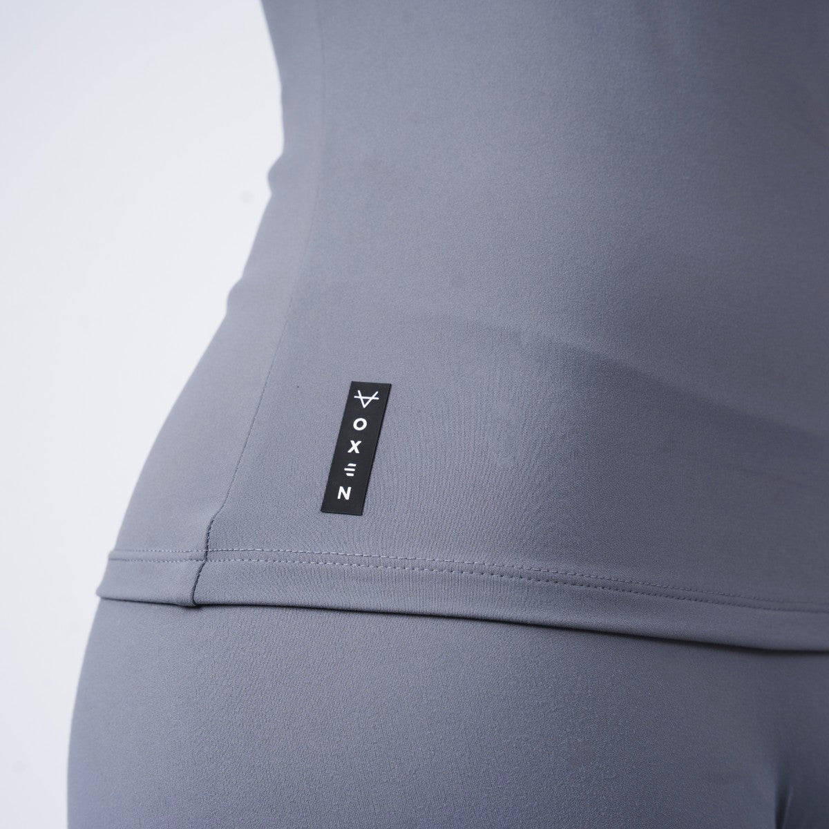 Close-up of side logo tag on Oxen Women’s Endure Sculpt Tank in Fossil grey.
