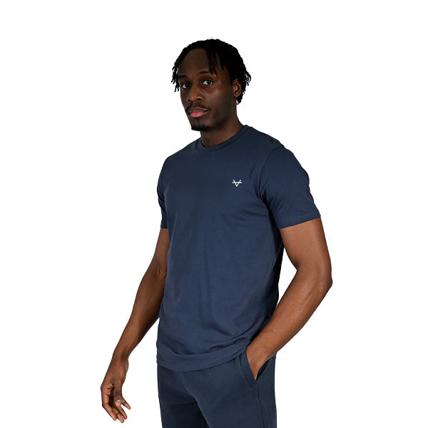 Man wearing a navy blue t-shirt with a small logo on a white background