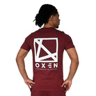 Person wearing a maroon t-shirt with a white oxen icon logo and text on the back, on a white background