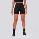 Person wearing black athletic shorts and high-top sneakers on a light gray background