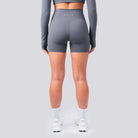 Person wearing gray athletic shorts with a brand logo on a light gray background