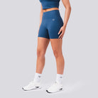 Person wearing blue athletic shorts and white sneakers on a gray background