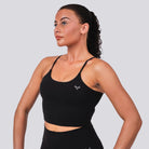 Woman wearing a black sports bra with a logo on a light gray background