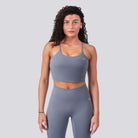 Woman wearing a gray sports bra and leggings on a light gray background