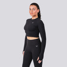 Woman wearing a black long-sleeve athletic top and leggings on a light gray background