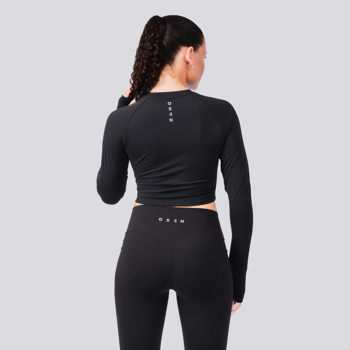 Person wearing a black athletic outfit with 'OXEN' branding on a gray background
